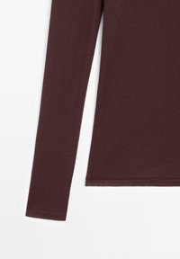 Haut ajusté à manches longues en tissu tricoté marron foncé, présenté de la taille au poignet sur fond blanc.