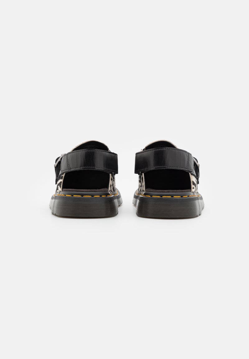 Schwarze Sandalen mit glänzender Oberfläche, verstellbaren Riemen, strukturierten Sohle und gelben Nähdetails. Offenes Rückendesign für Atmungsaktivität.