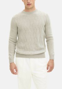 Lichtgrijze gebreide trui met een kabelpatroon, ronde halslijn en geribbelde manchetten en zoom, gecombineerd met witte plooibroek.