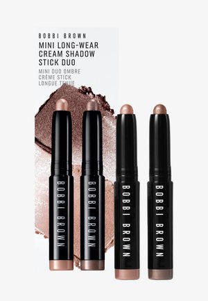 Quatre duos Bobbi Brown Mini Long-Wear Cream Shadow Stick noirs avec des teintes beige et marron de fards à paupières crème sur fond blanc.