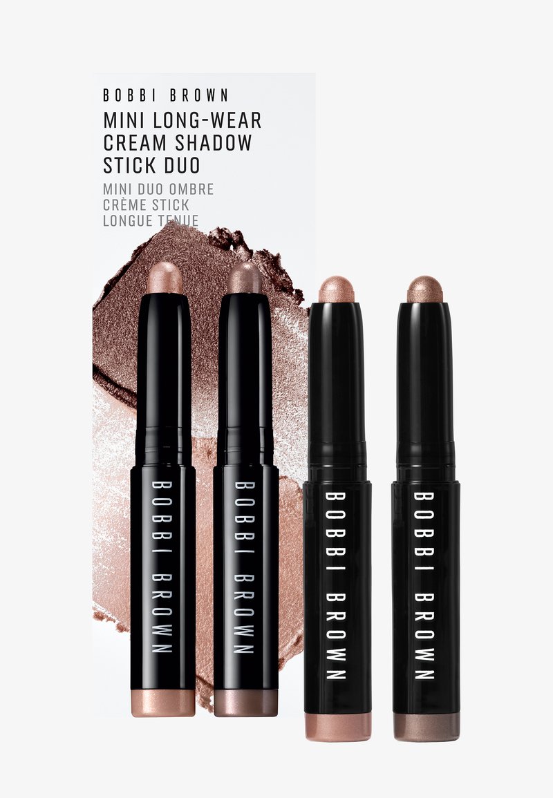 Four black Bobbi Brown Mini Long-Wear Cream Shadow Stick Duos with beige and brown cream eyeshadow shades on white background.