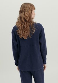 Marineblauer Fleecepullover mit langen Ärmeln und lockerer Passform. Bietet eine weiche Textur und eine Nahtdetails auf dem Rücken.