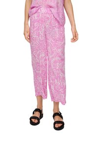 Pantalons à motif floral rose en tissu léger, avec une coupe loose et longueur cheville, associés à des sandales noires à semelles épaisses.
