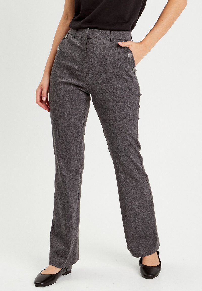 Pantalons droits gris en tissu texturé, dotés de boutons sur le côté, d'une taille haute et d'une légère évasement à l'ourlet, associés à des ballerines noires.