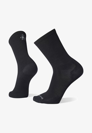 Chaussettes en mélange de coton noir avec une texture lisse, hauteur mi-mollet, talon et orteil renforcés, présentant un petit logo près de la cheville.