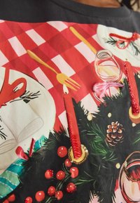 Grafik-T-Shirt mit einem festlichen Design, das aus einem rot-weißen Karomuster, Kerzen, Beeren und goldenen Akzenten besteht, sowie strukturierten Stickdetails.