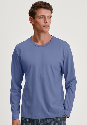 Lange mouwen shirt in lichtblauw, gemaakt van zacht materiaal, met een ronde hals en een ontspannen pasvorm. Gepaard met geblokte slaapshorts.