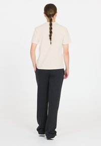 Beige t-shirt med kort ärm som matchas med svarta vida byxor. Mjukt tyg, avslappnad passform och synliga fickor på byxorna. Ren, enkel design.