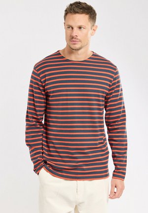 Langärmliges gestreiftes Hemd mit navyblauen und orangenen Streifen. Hergestellt aus weichem Stoff, mit Rundhalsausschnitt und lockerer Passform. Mit subtiler Logo-Akzentuierung.