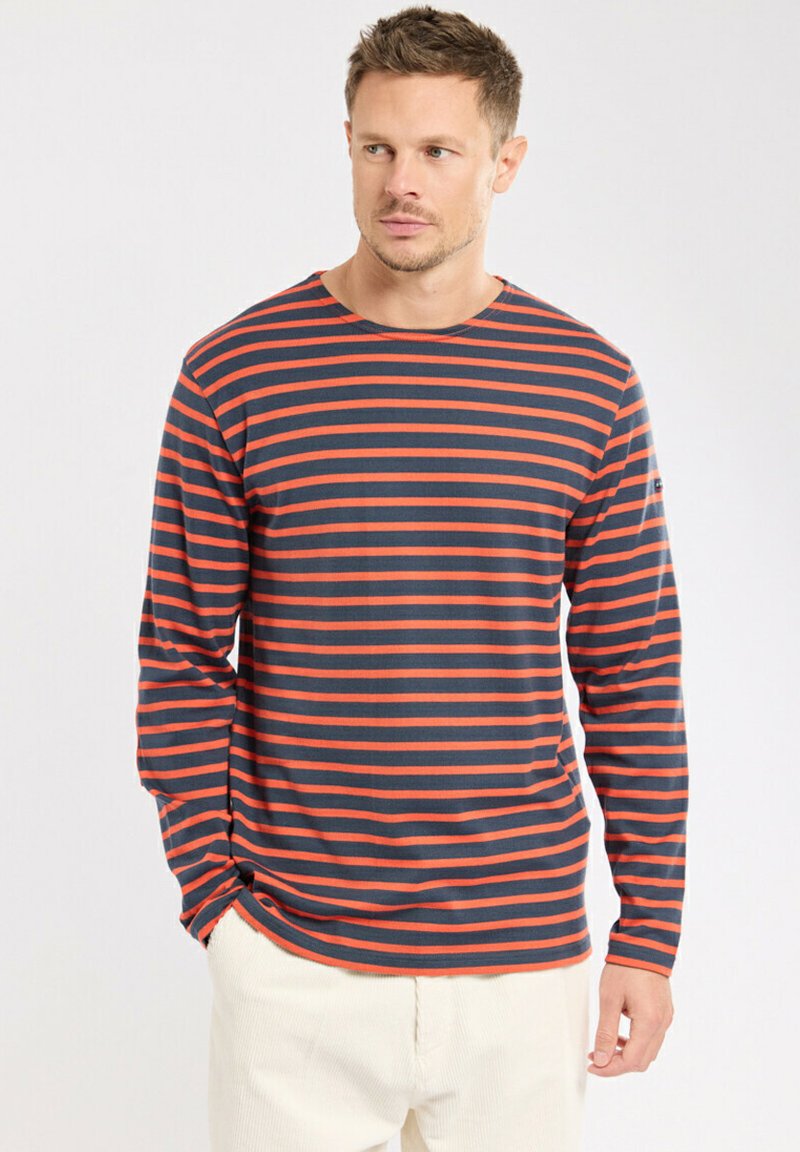 Chemise à manches longues rayée avec des rayures bleu marine et orange. Fabriquée en tissu doux, elle présente un col rond et une coupe décontractée. Accentuée par un logo discret.