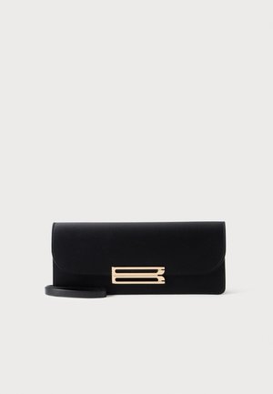 Bolso de mano rectangular negro con detalle decorativo de barra horizontal dorada y una delgada correa para la muñeca sobre un fondo liso.
