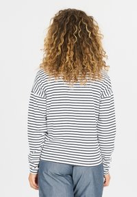 Gestreepte langemouwen shirt in wit en marineblauw, met een ontspannen pasvorm en verlaagde schouders, gecombineerd met losse denim broek.