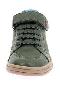 Sneaker verde in pelle con finitura testurizzata, dotata di lacci elastici, una cinturino in Velcro e una suola in gomma color beige. Inclusi accenti blu e rossi.