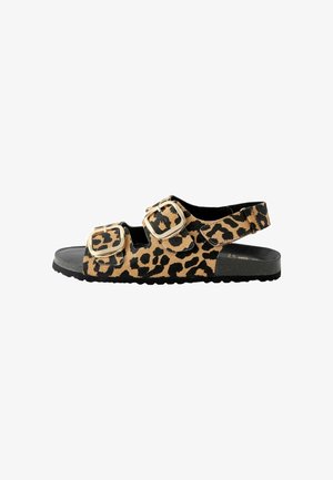 Leopard spausdinio šlepetės su dviem dideliais kvadratiniais sagtimis, juoda padas ir tekstūruota viršutinė dalis. Atvira pirštų ir kulno dalis, sukurta patogumui.