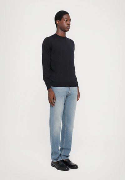 Black long-sleeve sweater paired with light blue straight-leg jeans and black shoes, displayed on a neutral background.
