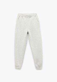 Lys grå sweatpants lavet af blødt stof, med elastisk talje, snoretræk og elastiske manchetter ved anklerne. To sidelommer.