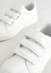 Weiße Sneakers aus strukturiertem synthetischem Material mit drei Klettverschlüssen und minimalistischer Gestaltung. Sie verfügen über eine Gummisohle und gestickte Akzente.