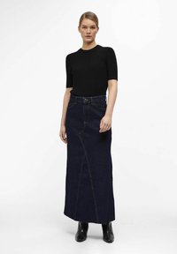Mørkeblå denim maxi-nederdel med lige snit, detalje på foran og høj talje, parret med en sort ribbet kortærmet top.