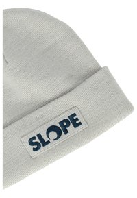 Grå stickad mössa med en nedvikt kant och en rektangulär patch som visar ordet "SLOPE" i marinblå bokstäver.