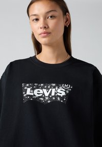 Felpa nera in cotone con collo rotondo. Presenta un logo bianco di Levi's circondato da un motivo stellato sul fronte.