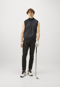 Majica brez rokavov v mornarsko modri barvi z zadrgo spredaj, črne oprijete hlače, bele golf čevlje z črnimi in rdečimi detajli ter bela golf rokavica.