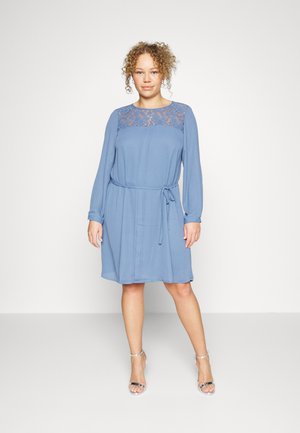 Veste azul-clara com um painel de renda no peito, mangas longas, um cinto amarrado na cintura e uma bainha até ao joelho. Textura de tecido suave.