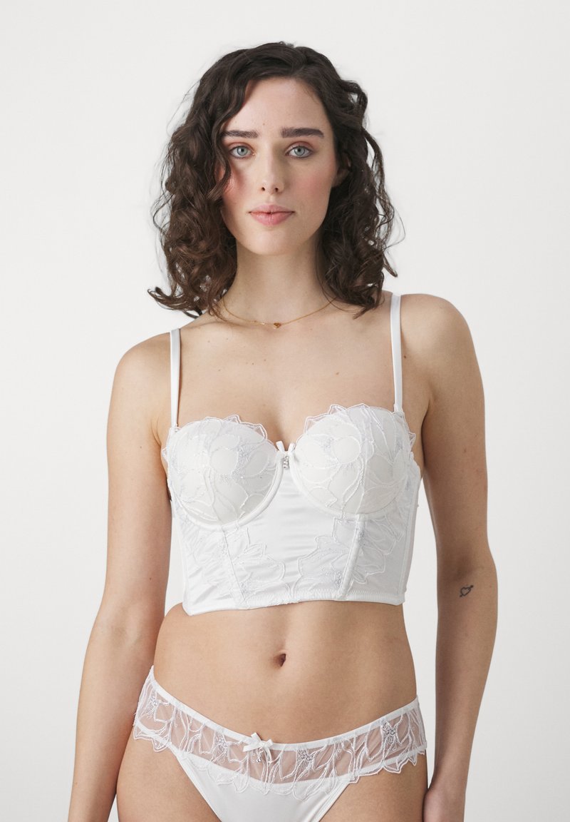 Witte lingerie set met een gestructureerde bustier met bloemendisplay, verstelbare bandjes en een bijpassende doorschijnende kanten string met strikkoord.