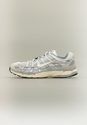 Zapatilla Nike P-6000 blanca y gris con paneles de malla y ante, suela acolchada y suela exterior negra, mostrada en perfil derecho sobre fondo neutro.