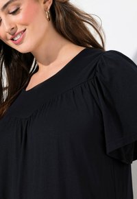 T-shirt nera con scollo rotondo e maniche puff che presentano tessuto arricciato, realizzata in morbido cotone.