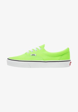 Niskie trampki Vans z jaskrawo neonowo zielonego płótna z białymi sznurowadłami, białą gumową podeszwą i czarnym paskiem.