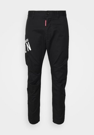 Mustad mustadest puuvillast pükstest, slim-fit lõikega, millel on valge graafiline trükk vasakul jalal ja tavapärane nööbikee vööl.