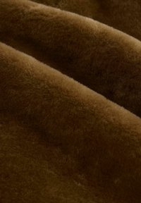 Blød brun stof med en plysset tekstur, der har en tæt, fuzzy overflade og en subtil glans. Materialet virker varmt og indbydende.