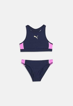 Tumesinist kaheosaline ujumisriietus roosade külgpaneelide ja kuldse Puma logoga topi ees keskel.