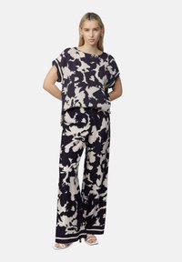 Blumenmuster-Zweiteiler bestehend aus einem locker sitzenden Oberteil und weit geschnittenen Hosen in Marineblau und Creme, gefertigt aus leichtem Stoff.