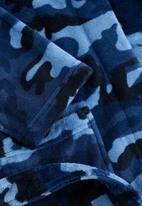 Fleece prikrývka v modro-čiernom maskáčovom vzore. Mäkká textúra s rôznymi odtieňmi modrej, so hladkými okrajmi a švami.