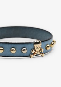 Bracciale in pelle blu con borchie metalliche e un accento di teschio e ossa incrociate in oro. Texture liscia e bordi arrotondati, design minimalista.