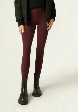 Maroon ribbed leggings with a high waist and stretchy material, paired with black leather ankle boots featuring a chunky sole.