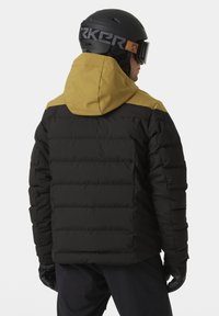 Schwarze Daunenjacke mit gelber Kapuze, gestepptem Design und elastischen Bündchen. Entwickelt für den Wintereinsatz, mit strukturiertem Stoff und kontrastierenden Farben.