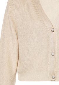 Cardigan bej deschis cu decolteu în V, fabricat dintr-un material texturat, cu fir metalizat strălucitor. Are trei nasturi decorativi pe partea din față.