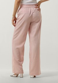 Roze wijde broek van textuurstof met een elastische tailleband en twee achterzakken, gecombineerd met metallic blokhak schoenen.