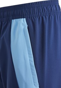 Marineblaue Sportshorts mit einem hellblauen Seiteneinsatz, elastischem Bund und glatter Textur. Das Design umfasst Farbakzente in kontrastierenden Farben.