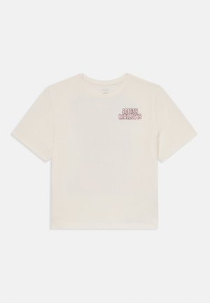 Crème-kleurige T-shirt met korte mouwen, gemaakt van zachte katoen, met een kleine roze afbeelding die "Squishmallows" op de linkerkant van de borst weergeeft.