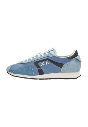 Scarpa da ginnastica azzurro chiaro con lacci bianchi, logo geometrico nero e bianco, dettagli in camoscio e suola bianca con battistrada nero.