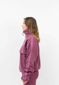 Fleece pullover in diep paars met hoge kraag, voorzak en grafisch accent. Voorzien van elastische manchetten en logo-details op de mouwen.