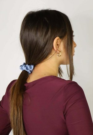 Light blue satin scrunchie holds long brown hair in a ponytail. The individual wears a burgundy top with a fitted design.