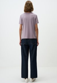 Liliowy t-shirt z krótkim rękawem, w luźnym kroju, w połączeniu z ciemnoniebieskimi, wysokimi dżinsami typu wide-leg, charakteryzującymi się prostym wzorem i minimalnym przeszyciem.