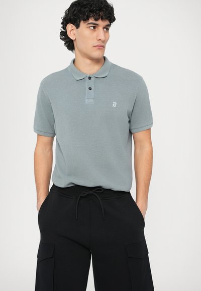 Γκρι πόλο μπλουζάκι με γιακά, τρεις κουμπότρυπες και κεντημένο λογότυπο· σετ με μαύρο φόρμα παντελόνι με πλαϊνές τσέπες.