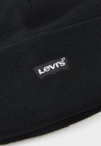 Berretto in maglia nera con una finitura strutturata e una toppa del logo Levi's bianca cucita. Design semplice e classico senza decorazioni.