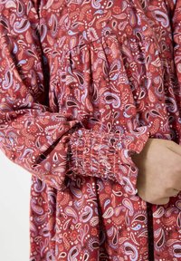 Rot und blau gemustertes Kleid im Paisleymuster mit gepufften Ärmeln und gerafften Bündchen, ausgestattet mit einem gerafften Oberteil und weichem, strukturiertem Stoff.