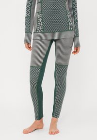 Conjunto deportivo en verde y gris con estampados que incluye una camiseta de manga larga y leggings ajustados con diseños a rayas y geométricos. Textura de tela suave.
